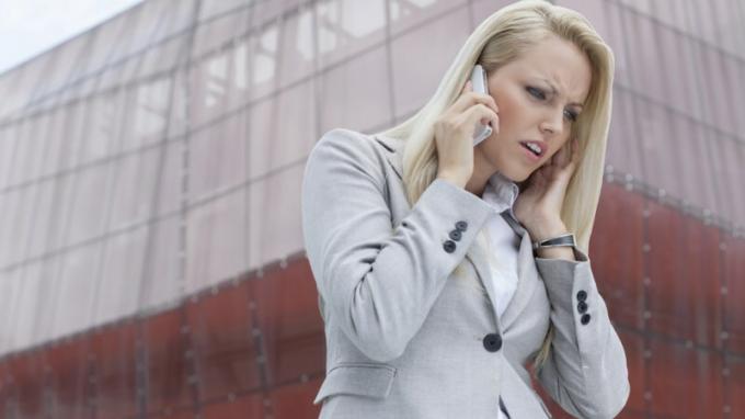Kobieta z ADHD słuchająca kogoś na telefonie komórkowym i denerwująca się przed wysokim budynkiem