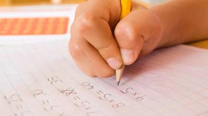 Ręka dziecka wypełniająca zadanie domowe za pomocą zakwaterowania matematycznego